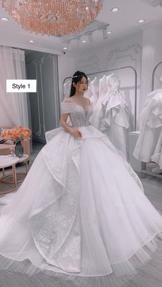 a woman in a white wedding dress standing next to some dresses