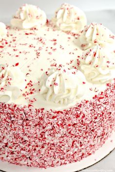 a cake with white frosting and red sprinkles