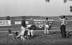 some people are standing near a race car