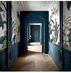 the hallway is decorated with tropical wallpaper and wood flooring, along with dark green painted walls