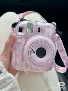 a pink camera with hello kitty on it is being held by someone's hand