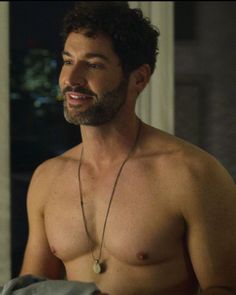 a shirtless man with no shirt on is looking at something in his hand and smiling