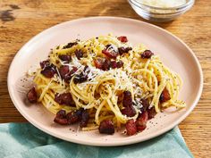 pasta with bacon and parmesan cheese on a plate next to a glass bowl