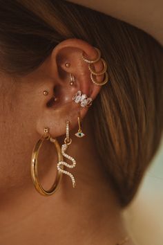 a close up of a person wearing gold ear rings with diamond and pearl decorations on them