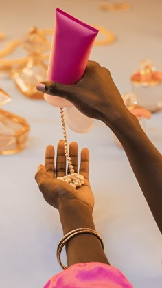 a woman is holding a pink cup in her hand while she holds it with both hands