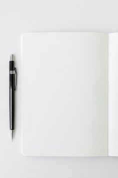 an open notebook with a pen on the top and blank pages in front of it