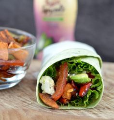 a wrap filled with meat and vegetables next to a bowl of salad