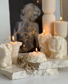 some candles are sitting on a table with flowers and pearls in front of the candle holders