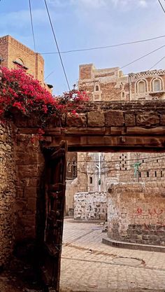 an old stone building with red flowers growing on it