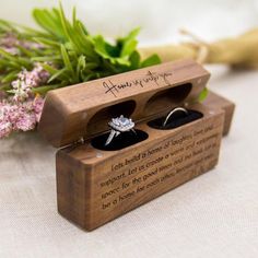 a wooden box with two wedding rings in it sitting on a table next to flowers