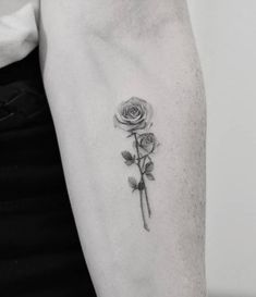 a woman's arm with a rose tattoo on the left side of her arm