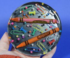 a person holding a plate with lots of different items on it and some paper clips in the middle