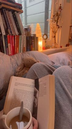 a person reading a book while holding a cup of coffee