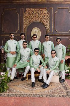 a group of men in green and white outfits posing for a photo on a rug