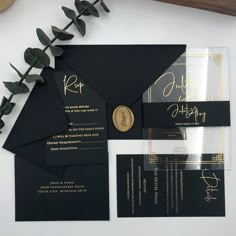 the black and gold wedding suite is displayed on a table with greenery in front of it