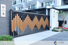 an orange and black gate is in front of a building with flowers on the sidewalk