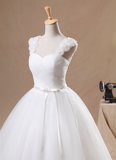 a white wedding dress on a mannequin with a sewing machine in the background