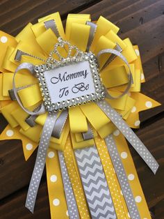 a yellow and gray ribbon wreath with the words mommy to be on it