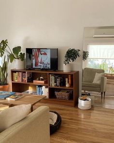 a living room filled with furniture and a flat screen tv on top of a wooden shelf