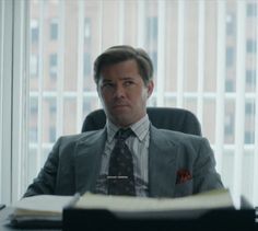 a man in a suit and tie sitting at a desk