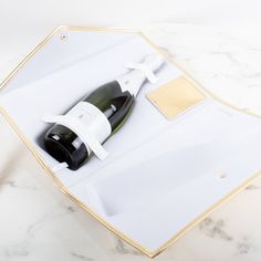 a bottle of wine in a white box on a marble counter top with gold trim