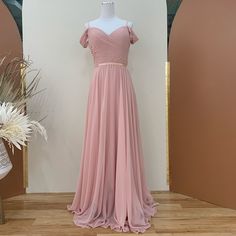 a pink dress is on display in front of a mirror and vase with white flowers