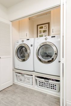 a washer and dryer in a white laundry room with open closet doors to the side