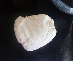 a heart shaped dough sitting on top of a black counter next to a glass bowl