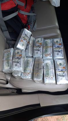 stacks of money sitting in the back seat of a car, next to a backpack