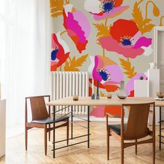 a dining room table and chairs in front of a wall with flowers painted on it