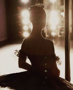 a woman wearing a tiara sitting in front of a window with light shining on her