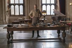 a man standing in front of a table with lots of clutter on top of it