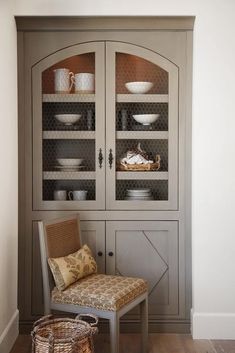 a chair sitting in front of a hutch with glass doors on it's sides