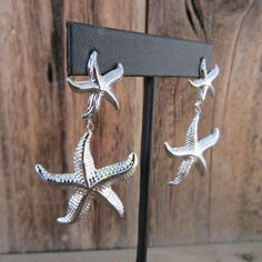 90s silver tone starfish dangle earrings. Textured. Stud backs. Nice quality. Light enough to  be comfy-- one weighs the equivalent of a quarter (coin). They are 2-3/8" long x 1-3/8" wide at widest part No noted flaws. Nickel Free Silver Starfish Earrings, Silver Starfish Earrings For Beach, Silver Drop Earrings With Starfish Charm, White Starfish Charm Star Earrings, Starfish-shaped Nickel-free Earrings For Gifts, Nickel-free Silver Starfish Earrings, Silver Ocean-inspired Earrings With Starfish Charm, Ocean-inspired Silver Earrings With Starfish Charm, Sterling Silver Starfish-shaped Earrings With Charm