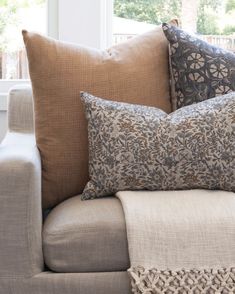 a couch with pillows on top of it in front of a window and some windowsills