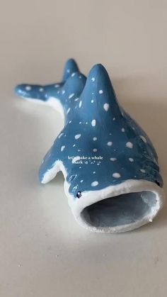 a ceramic blue and white whale toothbrush holder on a beige surface with polka dots