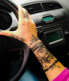 a woman's arm with a tattoo on it sitting in the driver's seat