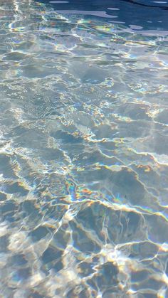 an empty swimming pool with clear water and sun reflecting off the surface on the water