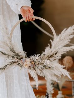 a person holding a basket with white feathers and flowers on the handle, in front of a table