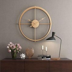 a clock mounted to the side of a wall next to a table with flowers on it