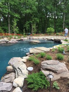 a man standing next to a pool surrounded by rocks