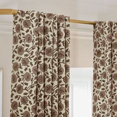 the curtains in this room are brown and white with flowers on them, along with an open window