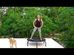 a woman standing on top of a trampoline next to a dog