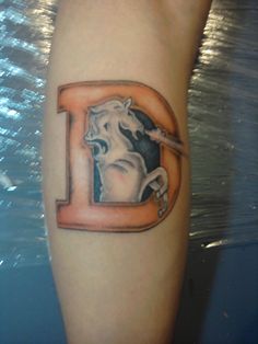 a tattoo on the leg of a person with a horse and letter d