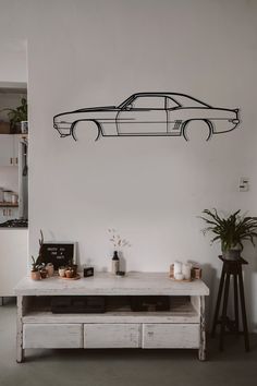 a room with a table, planters and a car wall decal on the wall