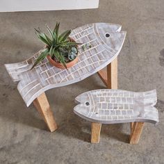 two wooden fish shaped planters sitting on top of a table next to a potted plant