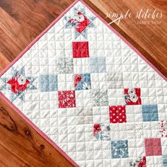 a red, white and blue quilted placemat on a wooden table with wood flooring