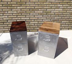 two metal filing cabinets sitting next to each other on top of a cement floor near a brick wall