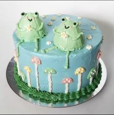 a cake decorated with two green frogs sitting on top of it