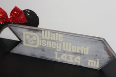 there is a sign that says walt world with minnie mouse ears on top of it